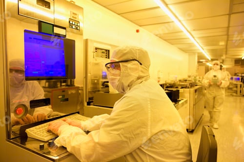 Preview: A Scientist In A Clean Suit Working On A Computer In The Silicon Wafer Manufacturing Room With Warm