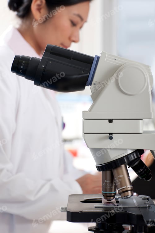 Preview: A Vertical Close Up Shot Of A Microscope With A Technician Working In A Blur Background In A