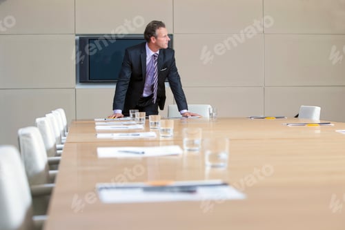 Preview: A Confident Businessman In A Formal Suit Leaning On The Table In An Empty Conference Room