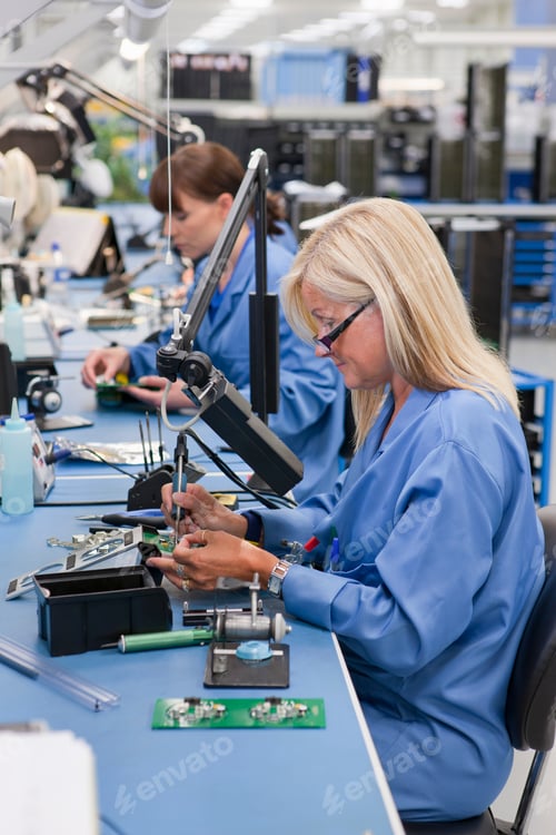 Preview: Vertical Profile Shot Of A Female Technician In An Assembly Line Soldering Component On A Printed