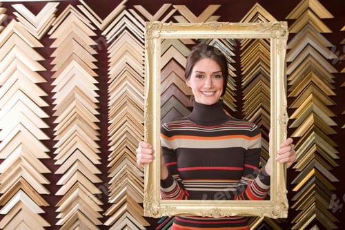 Preview: A Smiling Woman Holding A Golden Frame And Looking At The Camera Through It.