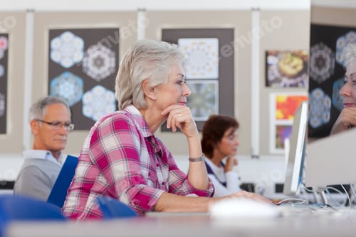 Preview: A Medium Shot Of A Senior Woman With Gray Hair Looking Seriously At A Computer In A Computer Lab.