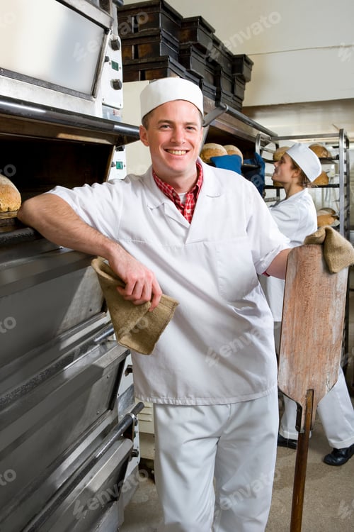 Preview: A Portrait Shot Of A Happy Baker Standing Next To An Oven With A Peel.
