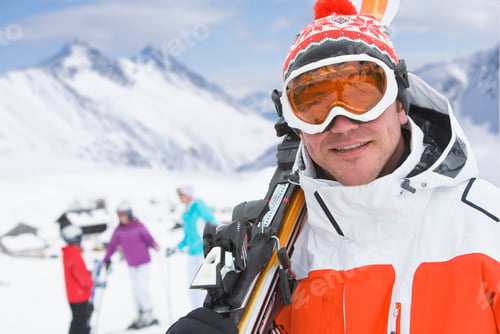 Preview: A Closeup Of A Handsome Skier Carrying His Skis On His Shoulder With His Family Standing In The