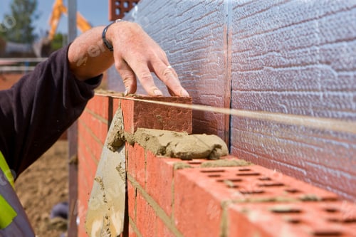 Preview: A Closeup Of Bricks Over Mortar Being Set In Alignment By The Bricklayer While Building A Wall