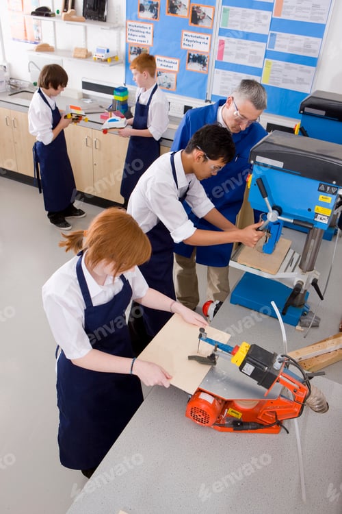 Preview: A High Angle Vertical Shot Of A Teacher Watching His Students Using A Saw Machine In A Class.