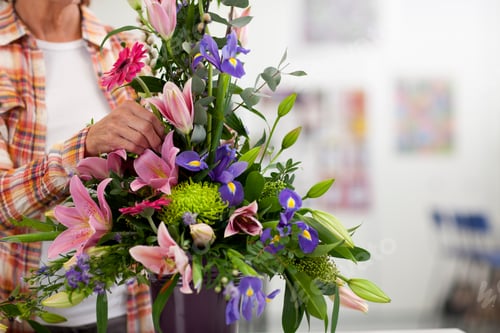 Preview: A Medium Shot Of A Senior Woman'S Hands Putting Flowers Into Floral Arrangement In A Classroom.