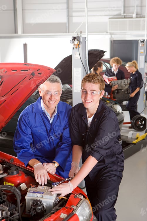 Preview: A Vertical View Of An Experience Trainer And A Young Automotive Student In Mechanic Uniform Smiling