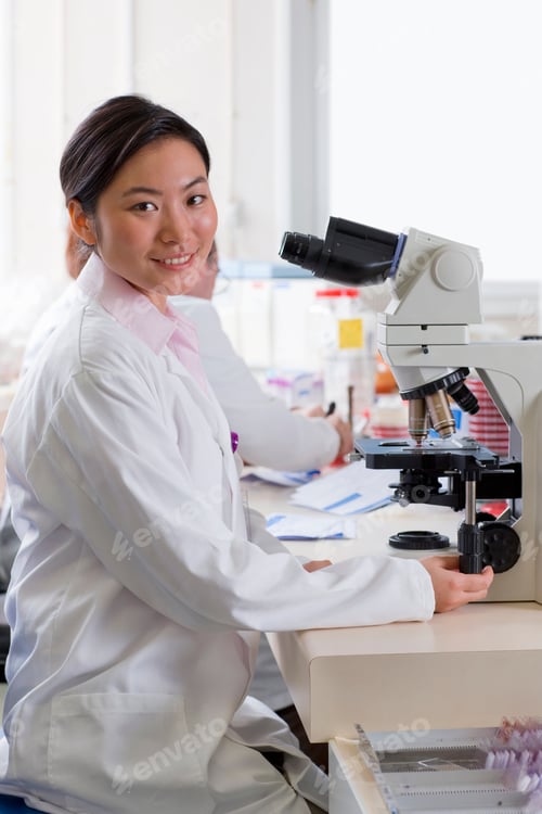 Preview: A Portrait Shot Of A Female Technician Smiling At Camera While Working With A Microscope In A