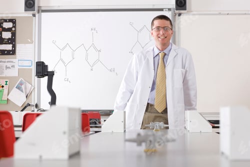 Preview: A Chemistry Teacher In A School Laboratory Wearing A Lab Coat Standing In Front Of A White Board