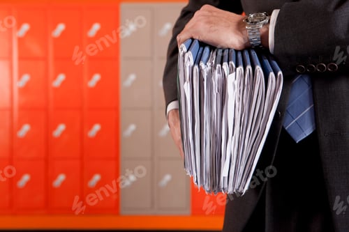 Preview: A Close Up Shot Of Teacher'S Hands Holding Files With Lockers In Background.