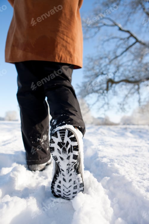 Preview: A Vertical Shot Of A Woman'S Feet Walking Through A Field Of Snow.