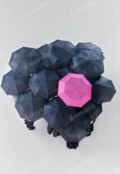 Preview: Overhead Shot Of A Group Of People Holding Black Umbrellas With One Pink Umbrella In Between.