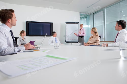 Preview: A Wide View Of A Conference Room With A Businesswoman Leading The Meeting While Standing Next To A