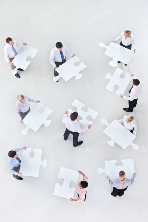 Preview: Overhead Shot Of Businesspeople Holding Large Jigsaw Puzzle Pieces In Their Hand Denoting Teamwork.