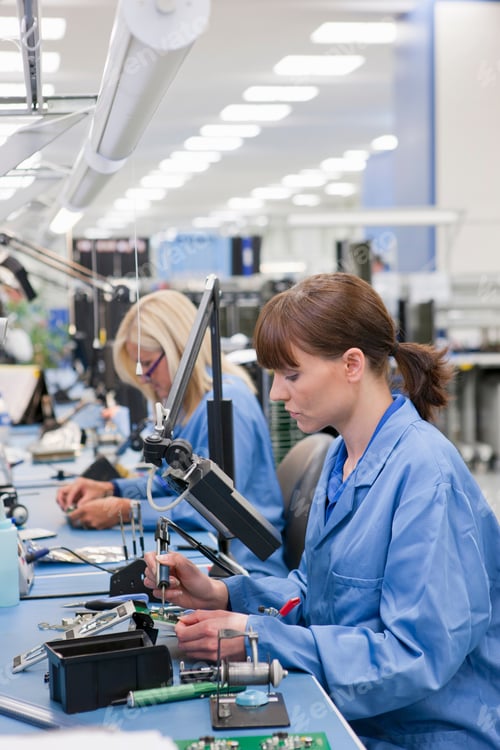 Preview: Vertical Waist Up Shot Of A Female Technician Soldering Carefully Over A Pcb On An Assembly Line In