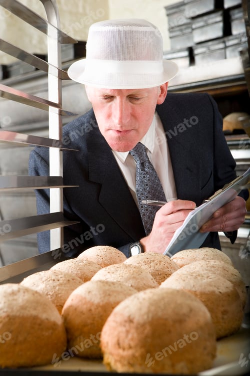 Preview: A Portrait Shot Of An Inspector Closely Examining Fresh Loaves Of Bread.