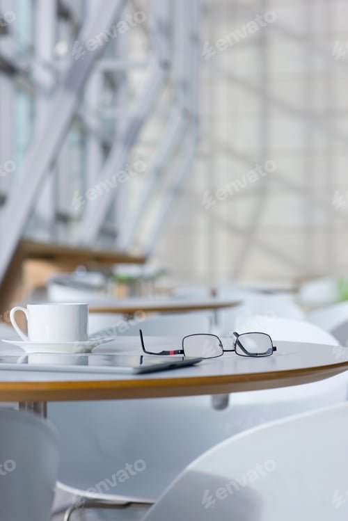 Preview: A Vertical Close Up Shot Of A Digital Tablet, Eyeglasses And A Coffee Cup On A Table In A Caf�.