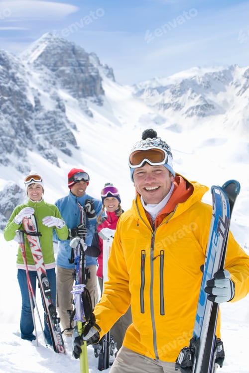 Preview: An Vertical View Of An Adventurous Man Holding Skis While Smiling At The Camera On A Mountain Top