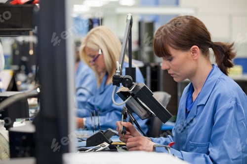 Preview: Horizontal Profile Shot Of A Female Technician In An Assembly Line Soldering Component On A Printed
