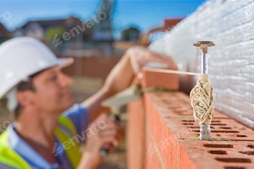 Preview: A Side View Of Bricklayer Setting Bricks On A Wall In Alignment With Line Pins And Thin Rope In