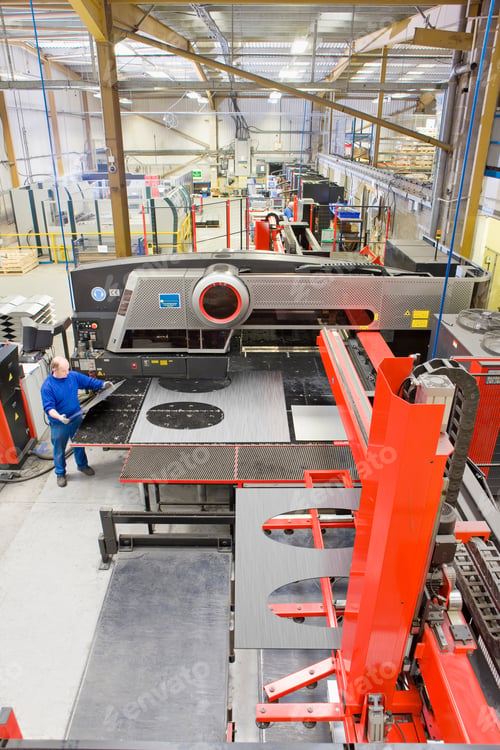 Preview: A Vertically Wide View Of A Large Factory With A Mature Adult Man Working On A Sheet Metal Press