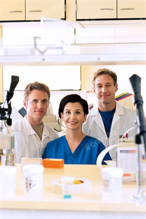 Preview: A Portrait Of Smiling Pharmacists Wearing Scrub Suits And Lab Coats In The Hospital Pharmacy With