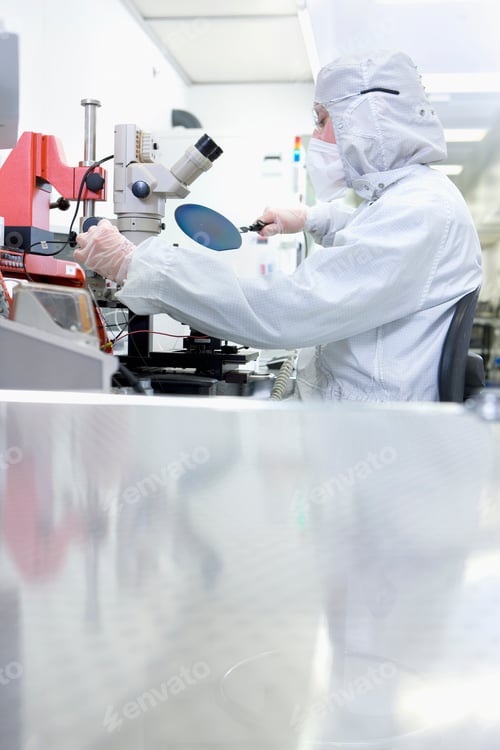 Preview: A Vertical View Of A Scientist In Clean Suit Examining The Silicon Wafer While Sitting Next To A