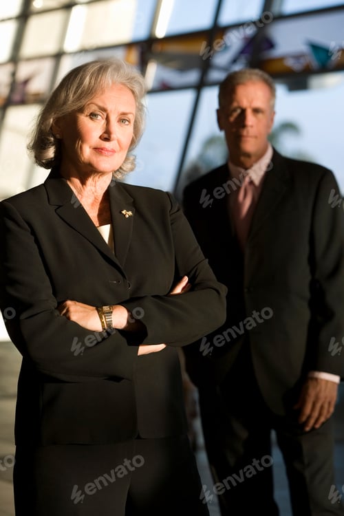 Preview: A Portrait Shot Of A Senior Businesswoman In A Black Suit Standing With Her Arms Crossed And