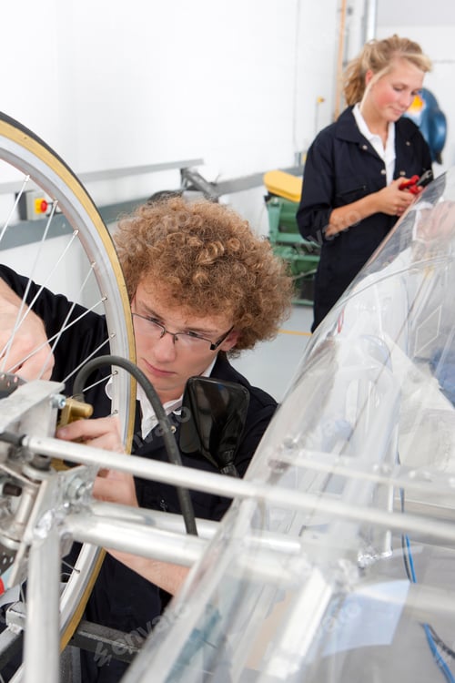Preview: A High Angle Portrait Shot Of A Young Boy Working On A Electric Vehicle Prototype In A Vocational