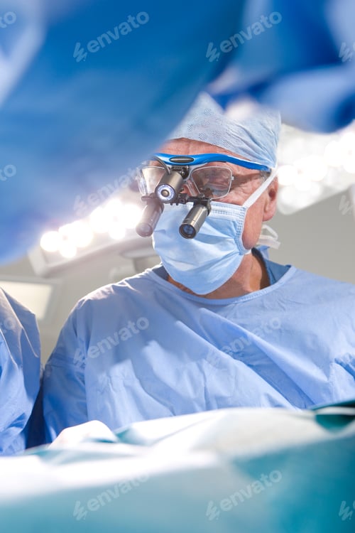 Preview: A Vertical View Of A Senior Surgeon In Selective Focus Wearing Advanced Magnifying Loupe During An