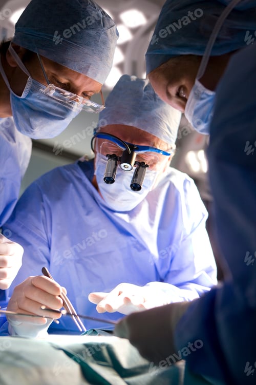 Preview: A Vertical View Of A Senior Surgeon Wearing Surgical Binocular While Performing An Intricate