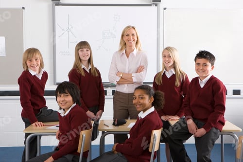 Preview: A Wide Shot Of Smiling Students And A Proud Teacher Posing And Standing With Her Arms Crossed In A