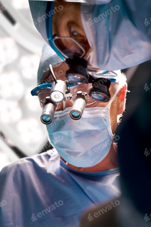 Preview: A Vertical View Of Two Professional Surgeons Performing An Operation While Looking Through The