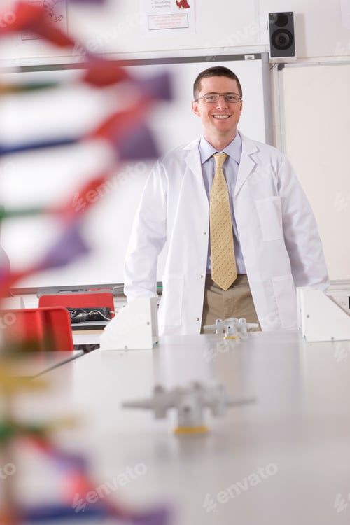 Preview: A Vertical Front View Of A Chemistry Teacher Smiling At The Camera In A School Lab Wearing A Lab