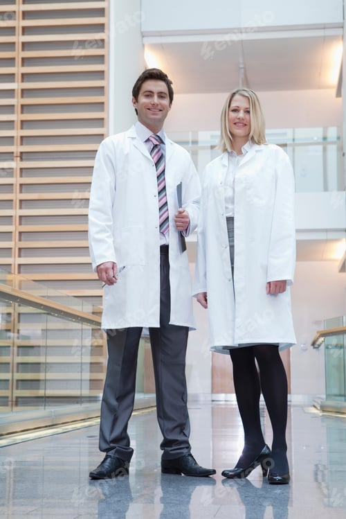 Preview: A Low Angle Portrait Of Smiling Doctors Wearing Lab Coats In A Hospital Corridor