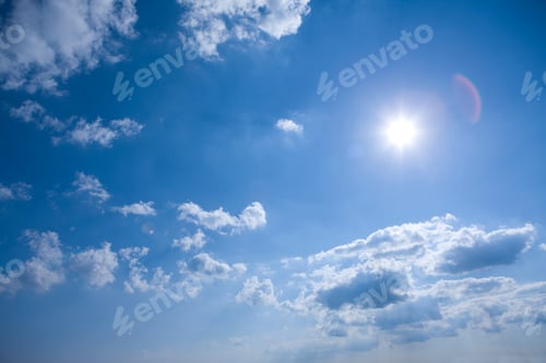 Preview: A Wide View Of A Blue Sky With White Floating Clouds And Glowing Sun Causing A Spectacular Lens