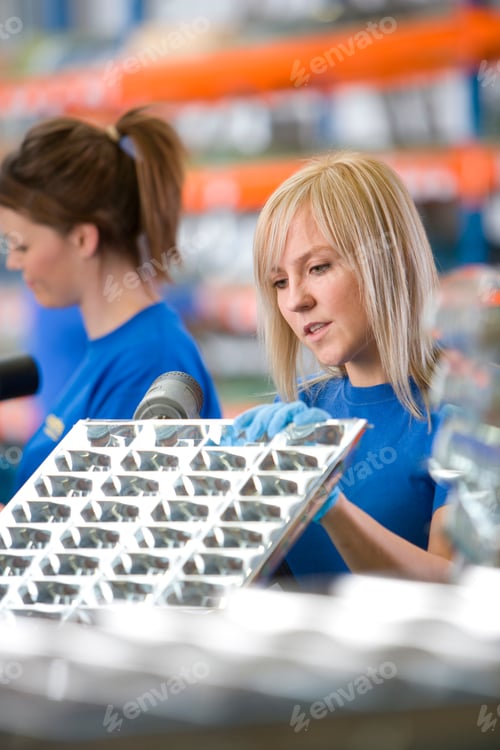 Preview: A Portrait Close Up Shot Of A Young Blonde Female Worker Drilling Aluminum Light Fittings.