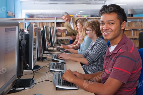 Preview: A Medium Shot Of A Happy Young Man Smiling At Camera While Using A Computer In A Computer Lab With