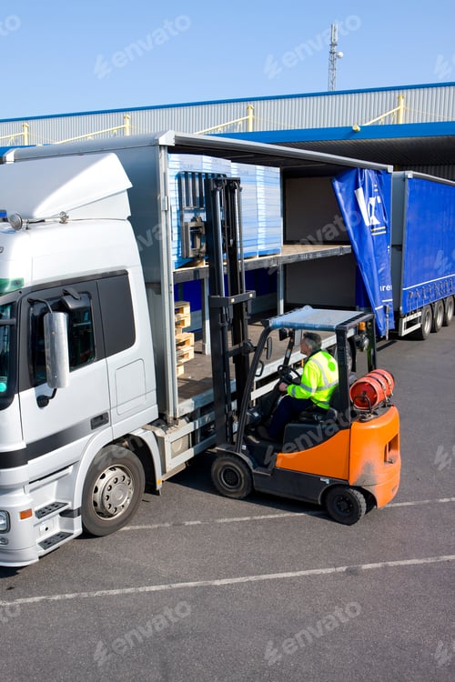 Preview: A Middle Aged Worker Driving And Using The Forklift To Load Packages On A Semi-Truck In Vertical