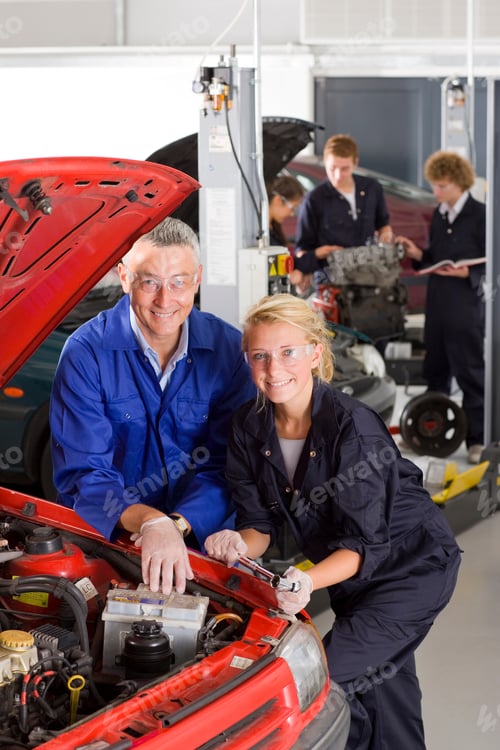 Preview: A Vertical View Of An Experienced Trainer And A Young Student In Mechanic Uniform Smiling At The
