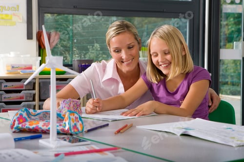 Preview: A Shot Of A Happy Teacher Helping Her Young Student With The Drawing In A Classroom.