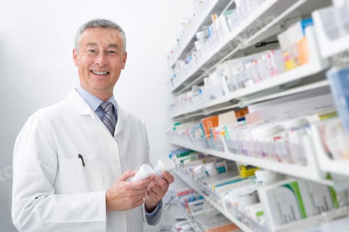 Preview: A Smiling Pharmacist Looking At The Camera And Holding Medicine Bottles In His Hands.