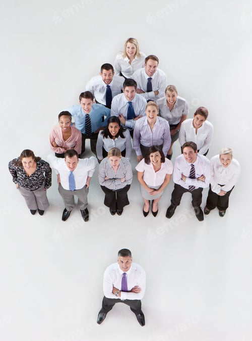 Preview: Overhead Shot Of A Group Of Businesspeople Standing In A Pyramid Formation Behind Their Boss