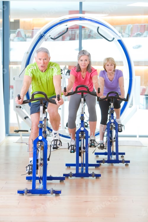 Preview: A�Vertical�Portrait Of�Fit And Healthy�Senior Adults Working Out On�Stationary�Exercise Bikes�In A