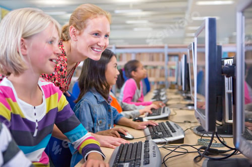 Preview: A Medium Shot Of A Smiling Teacher Looking At A Young Blonde Girl'S Computer Screen In A Computer