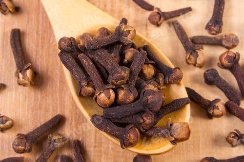 Preview: Heap Of Brown Cloves On Wooden Spoon Lying On Wooden Table, Seasoning For Baking And Cooking