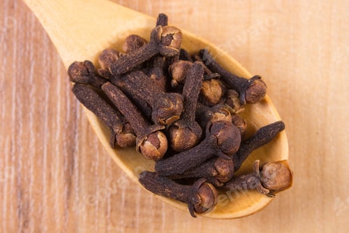 Preview: Heap Of Brown Cloves On Wooden Spoon Lying On Wooden Table, Seasoning For Baking And Cooking