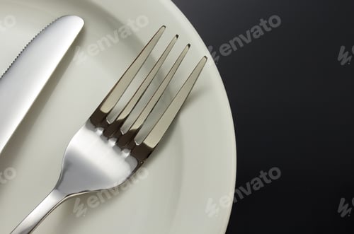 Preview: Knife And Fork At Plate On Black Background