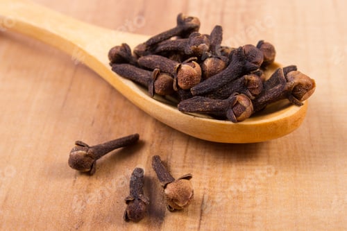 Preview: Heap Of Brown Cloves On Wooden Spoon Lying On Wooden Table, Seasoning For Baking And Cooking